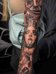 Tattoo featuring a face like that from a horror movie; black blood and white eyes coming from eyes and tongue