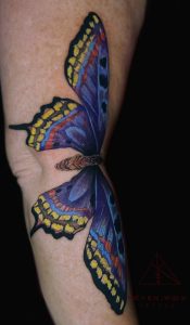 A color ink tattoo of a blue and yellow butterfly